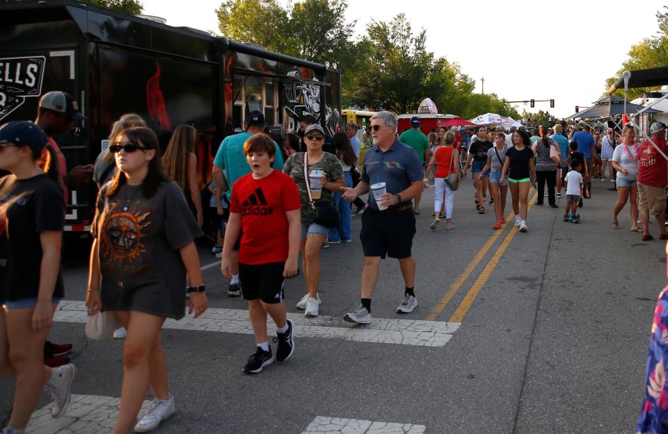 People walk on July 15 by food trucks during Heard on Hurd in Edmond.