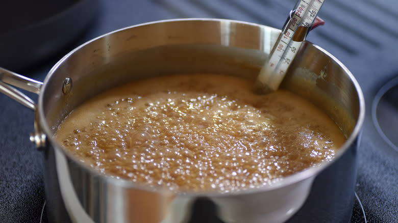 Candy thermometer in boiling fudge mixture in a metal saucepan on a stove