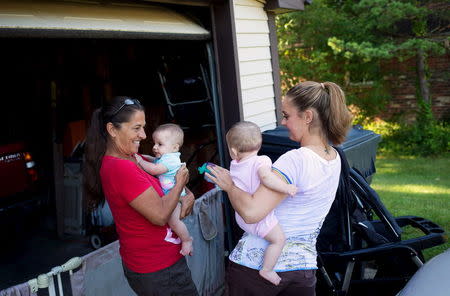 Heather Padgett, along with her mother Debi Padgett (L), prepares her daughters Kinsley and Kiley for a walk outside their home in Cincinnati, Ohio July 16, 2015. REUTERS/Aaron P. Bernstein