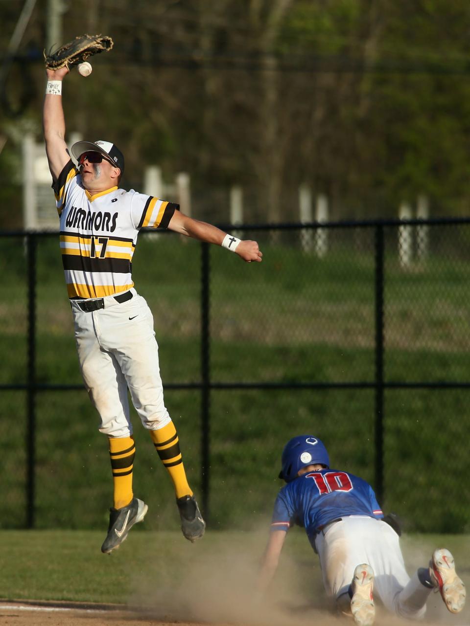 Licking Valley's Gunner Bowman dives into first on a bunt single as Watkins Memorial's Brayden Windnagel leaps for a high throw on Monday.