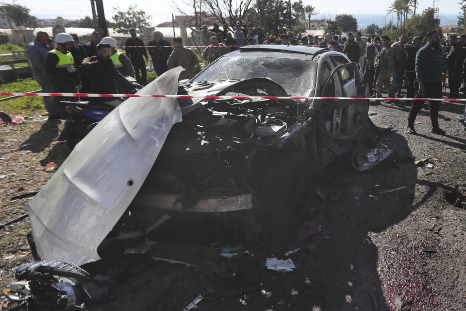 Lebanese army soldiers and civil defence workers gather around a destroyed car near the coastal town of Jadra, south Lebanon, Saturday, Feb. 10, 2024. An apparent Israeli drone strike hit a car near Lebanon's southern port city of Sidon Saturday killing at least two people and wounded others, security officials said. (AP Photo/Mohammed Zaatari)