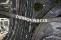 Varias personas cruzan un puente peatonal que tiene escrita la palabra "Democracia", en Sao Paulo, Brasil, el 26 de octubre de 2022. El país se prepara para la celebración del balotaje de las elecciones presidenciales el 30 de octubre. (AP Foto/Matías Delacroix)