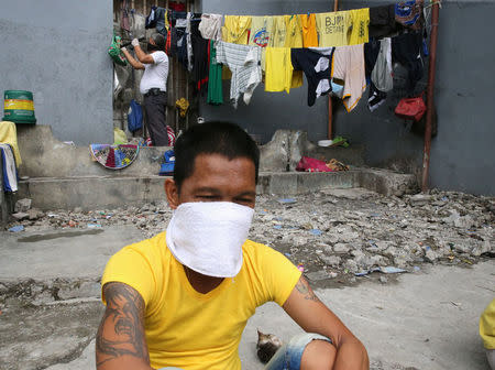 A detainee sits next to authorities searching through the belongings of prisoners for illegal contraband inside the Manila City Jail in metro Manila, Philippines October 16, 2017. REUTERS/Romeo Ranoco