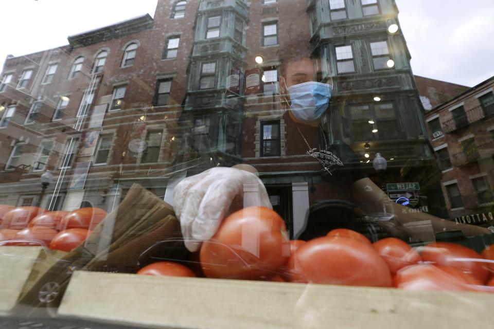 FILE - In this May 12, 2020 file photo, a worker places tomatoes in the window of Monica's Mercato & Salumeria food shop during the coronavirus pandemic, in the North End neighborhood of Boston. Small businesses can still get help from the government’s coronavirus relief plan after Congress extended the Paycheck Protection Program until Aug. 8. The program that had been set to expire last week still has more than $130 billion left after giving out more than 4.8 million loans since its April 3 start. (AP Photo/Steven Senne, File)