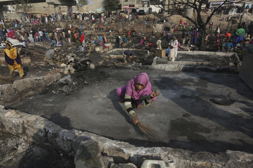 CAPTION CORRECTION: CORRECTS YEAR: A woman sweeps an area of her home following a fire that gutted a neighborhood in Karachi, Pakistan, Wednesday, Jan. 22, 2020. Hundreds of huts were burnt to ashes as fire erupted making dozens of families homeless in a slum of Karachi, local media reported. (AP Photo/Fareed Khan)