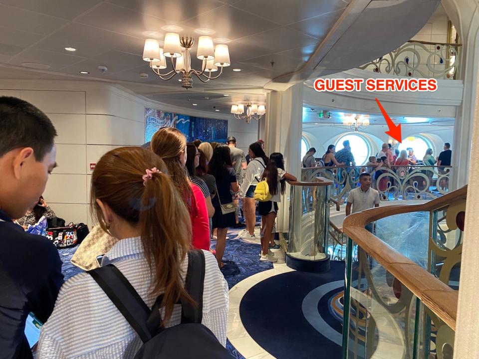 People wait in line to visit Guest Services onboard the Disney Wish.