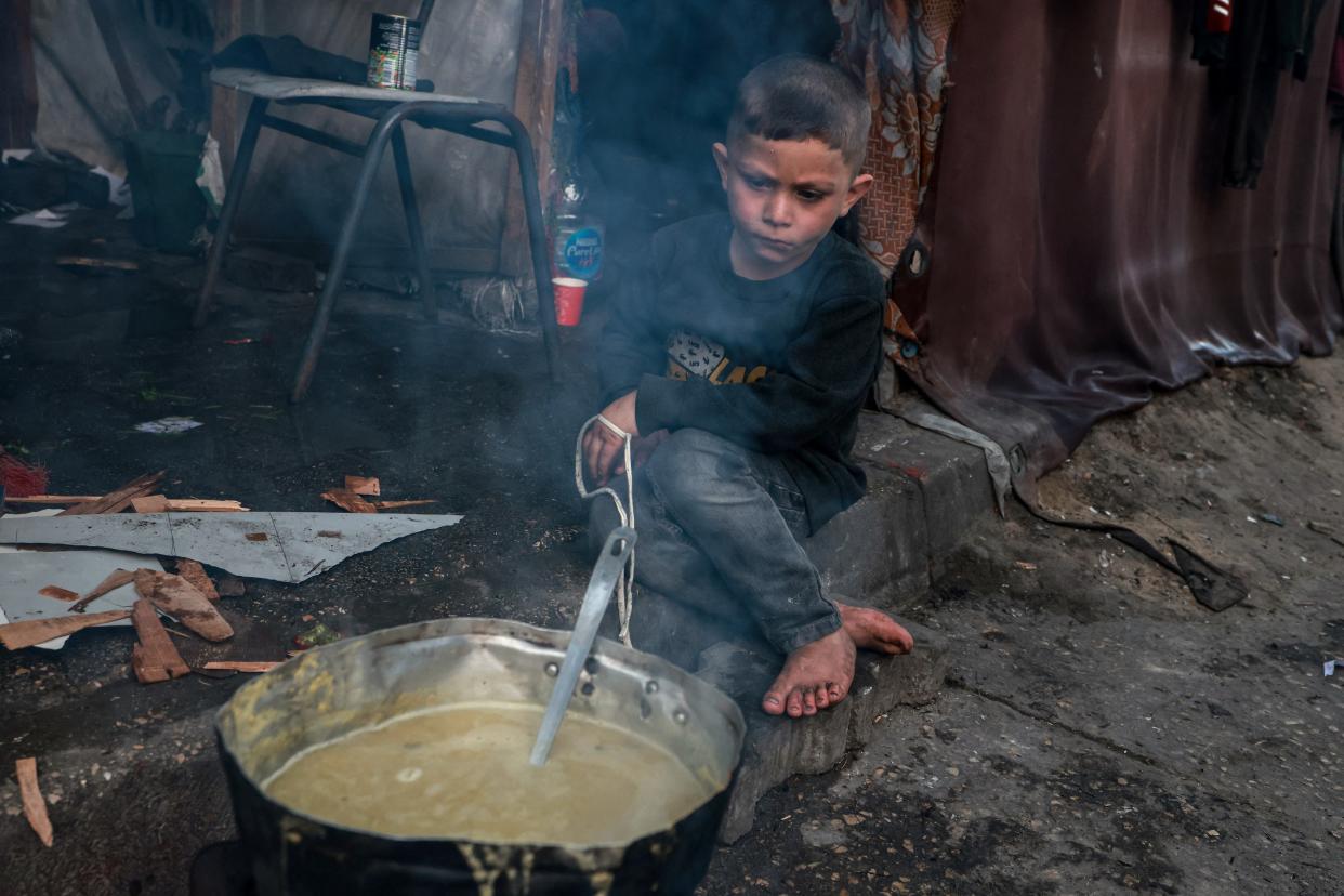 A Palestinian boy waits for an "iftar" meal, or breaking of fast, on the second day of the Muslim holy fasting month of Ramadan, at a camp for displaced people in Rafah in the southern Gaza Strip on March 12, 2024, amid ongoing battles between Israel and the militant group Hamas.