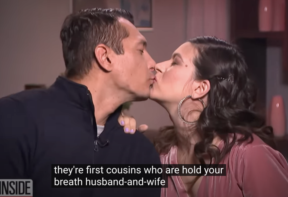 A couple, who are first cousins, kiss while sitting indoors. The caption reads, "they're first cousins who are hold your breath husband-and-wife."