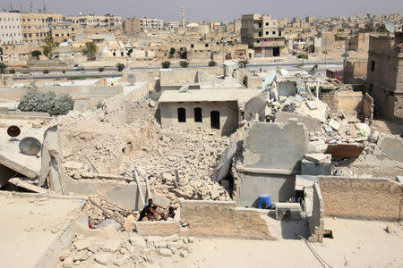 Civil defense members sit amid the rubble of damaged buildings after an airstrike in the rebel held Bab al-Nairab neighborhood of Aleppo, Syria, August 25, 2016. REUTERS/Abdalrhman Ismail