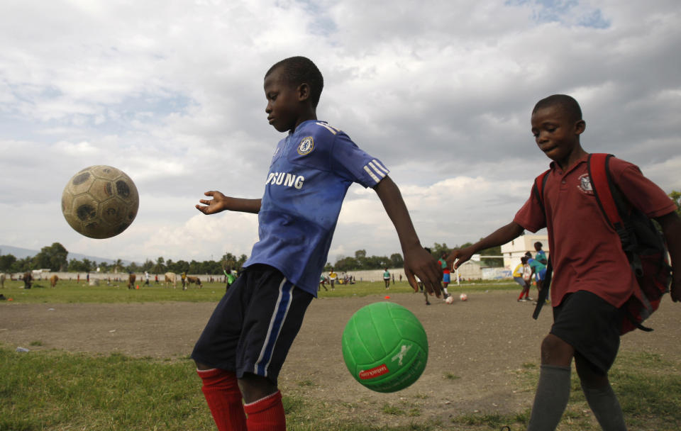 In this May 17, 2012 photo, youths play with soccer balls in a field that is part of the L'Athletique D'Haiti sports program at the northeastern edge of Cite Soleil, in Port-au-Prince, Haiti. A local sports hero, a New York real estate developer and a well-known architect are teaming up to build a soccer stadium in Cite Soleil, hoping to revive the seaside shantytown. The organizers also hope the stadium, scheduled to break ground within six months and due to be built by the end of 2013, will bring an initial 500 jobs and inject commerce into the shanty city, where politicians to pay residents to fight their battles as proxy forces. (AP Photo/Dieu Nalio Chery)