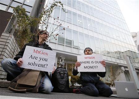 Kolin Burges (R), a self-styled cryptocurrency trader and former software engineer who came from London, and fellow protester Aaron hold placards as they demonstrate against Mt. Gox, in front of the building where the digital marketplace operator is housed in Tokyo February 25, 2014. REUTERS/Toru Hanai