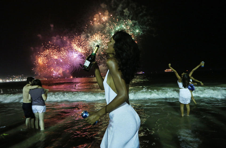 <p>JAN. 1, 2017 – Revelers celebrate during fireworks marking the start of the New Year on Copacabana beach in Rio de Janeiro, Brazil. Brazilian revelers annually mark the turn of midnight on January 1st with fireworks along the famed beach. This year’s fireworks were shortened to twelve minutes due to the economic crisis facing the state and country. (Photo: Mario Tama/Getty Images) </p>