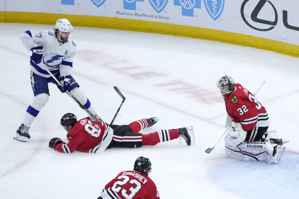 Chicago Blackhawks' Caleb Jones (82) blocks the shot of Tampa Bay Lightning's Victor Hedman as goaltender Alex Stalock also defends during the first period of an NHL hockey game Tuesday, Jan. 3, 2023, in Chicago. (AP Photo/Charles Rex Arbogast)