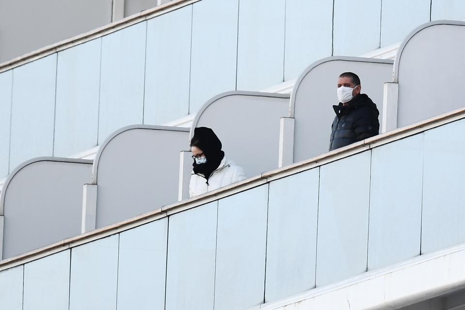 Passengers stand on balconies on the Diamond Princess cruise ship, with around 3,600 people quarantined onboard due to fears of the new coronavirus, at the Daikoku Pier Cruise Terminal in Yokohama port on February 10, 2020. - Around 60 more people on board the quarantined Diamond Princess cruise ship moored off Japan have been diagnosed with novel coronavirus, the country's national broadcaster said on February 10, raising the number of infected passengers and crew to around 130. (Photo by CHARLY TRIBALLEAU / AFP) (Photo by CHARLY TRIBALLEAU/AFP via Getty Images)