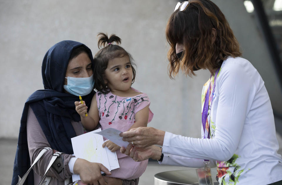 A volunteer interacts with a child evacuated from Kabul, Afghanistan at Washington Dulles International Airport, in Chantilly, Va., on Saturday, Aug. 28, 2021. (AP Photo/Gemunu Amarasinghe)