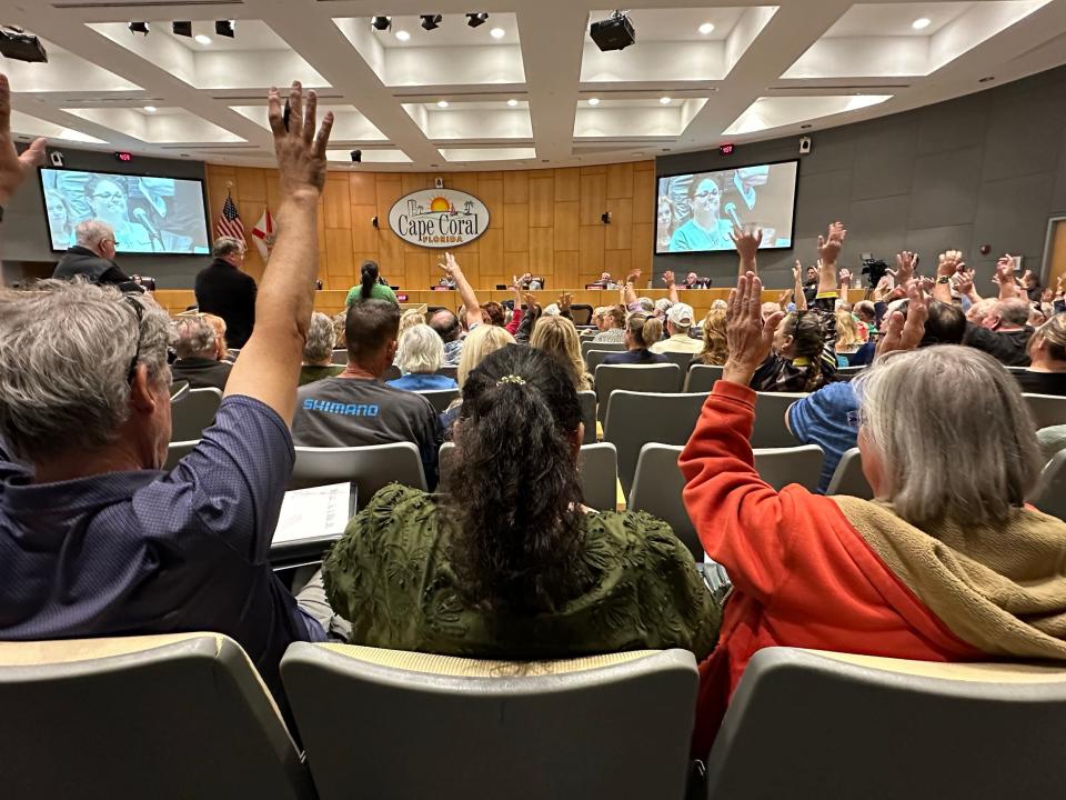 Cape Coral residents wave their hands in agreement with a speaker who spoke against the city council's new stipends.