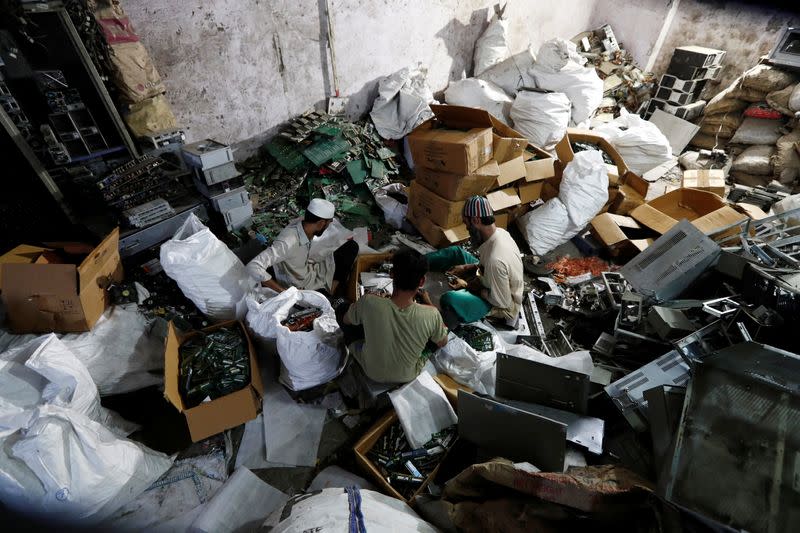 Men recycle e-waste from computers at a workshop in New Delhi