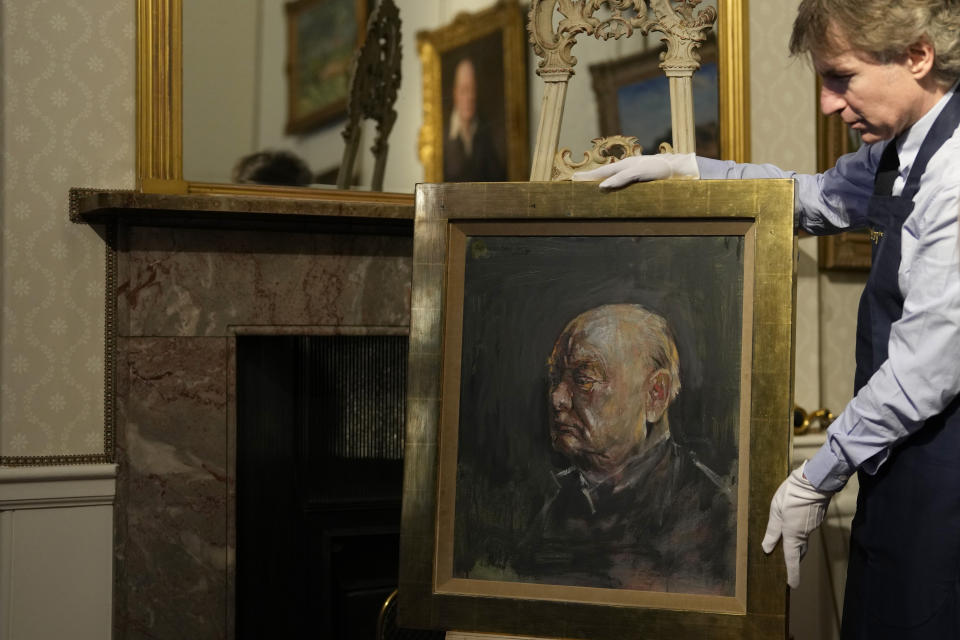 A member of staff from Sotheby's poses for the media with a portrait of the iconic former British Prime Minister Winston Churchill, painted by Graham Sutherland in 1954, at Blenheim Palace, Woodstock, England, Tuesday, April 16, 2024. The portrait will be sold at auction on June 6 with an estimated price of 500-800,000 pounds sterling (US621, 000-1,000,000). Churchill was born at Blenheim Palace on Nov. 30, 1874. (AP Photo/Alastair Grant)