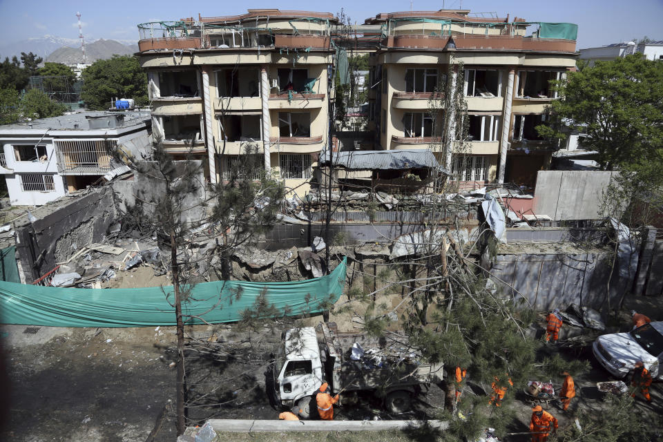 Afghan municipality workers clean a road in front of the damaged buildings, a day after an attack in Kabul, Afghanistan, Thursday, May 9, 2019. Taliban fighters attacked the offices of a U.S.-based aid organization in the Afghan capital on Wednesday, setting off a huge explosion and battling security forces in an assault, the Interior Ministry said. (AP Photo/Rahmat Gul)