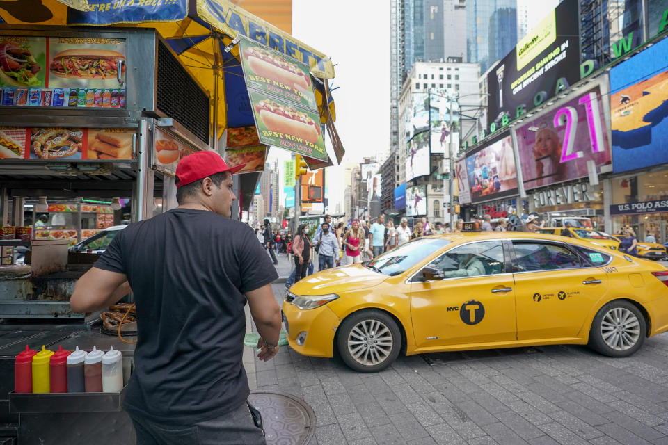 Youssef Mohamed moves his hot dog cart into his spot on 45th Street in New York's Times Square, Wednesday, Sept. 14, 2022. It's becoming clearer that New York City's recovery from the pandemic will be drawn out and that some aspects of the city's economic ecosystem could be changed for good. More workers returned to their offices as the summer ended. But those limited numbers mean continued hardship for New Yorkers whose jobs are built around the commuting class. (AP Photo/Mary Altaffer)