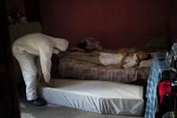 A worker of SOS Funeral, wearing protection equipment, prepares to remove the body of Eldon Cascais, who according to relatives, had pre-existing conditions and died at his house after having trouble breathing, amid the new coronavirus outbreak in Manaus, Brazil, Saturday, May 9, 2020. (AP Photo/Felipe Dana)