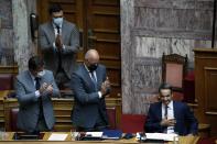 Greece's Prime Minister Kyriakos Mitsotakis, right, thanks his party's lawmakers after his speech during a parliament debate in Athens, Wednesday, Aug. 26, 2020. Mitsotakis says his country is planning to exercise its legal right to extend territorial waters along its western coastline from six to 12 nautical miles. The plan was announced Wednesday as Greece remains locked in an escalating dispute over maritime boundaries with neighbor Turkey, with a survey mission and military exercises currently being held in east Mediterranean waters claimed by both countries. (AP Photo/Thanassis Stavrakis)