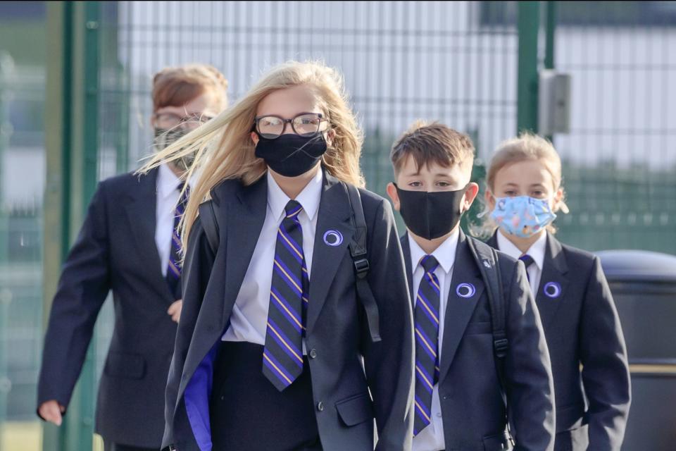 <p>Pupils wearing masks on their way to school</p> (PA)