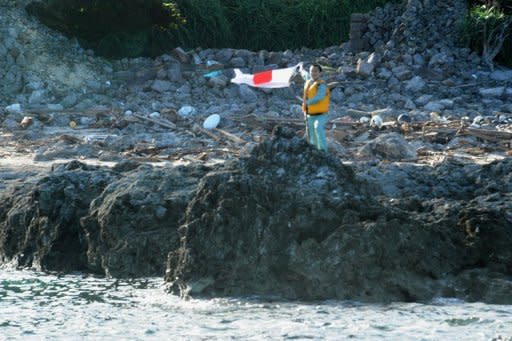 A Japanese activist waves the country's flag after landing on the disputed islands in the Eash China Sea on August 19. About a dozen Japanese nationalists raised their country's flag on Uotsurijima island, prompting protests in cities across China