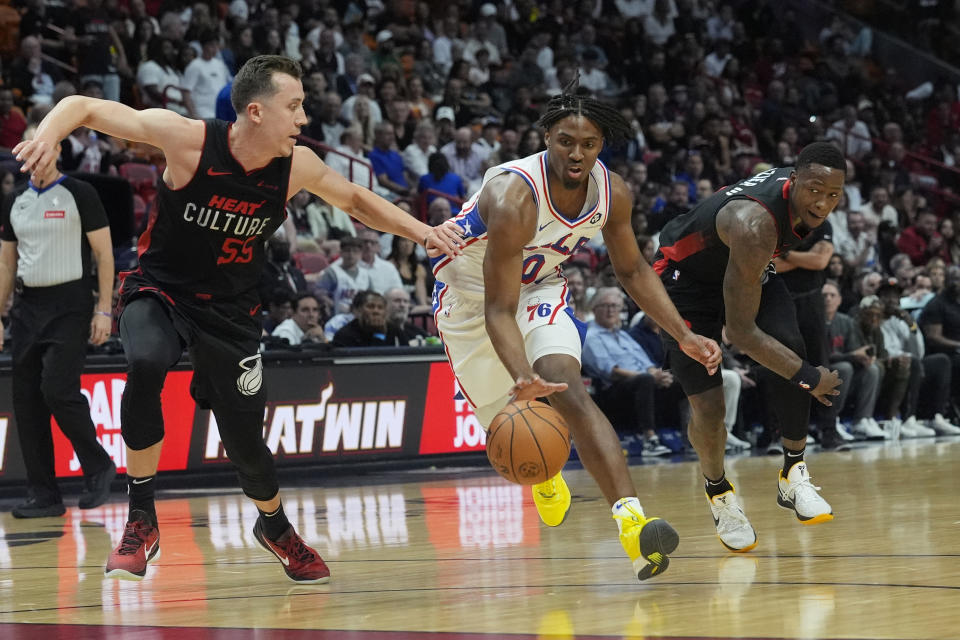 Philadelphia 76ers guard Tyrese Maxey (0) dribbles the ball as Miami Heat forwards Duncan Robinson (55) and Haywood Highsmith defend during the first half of an NBA basketball game, Thursday, April 4, 2024, in Miami. (AP Photo/Marta Lavandier)