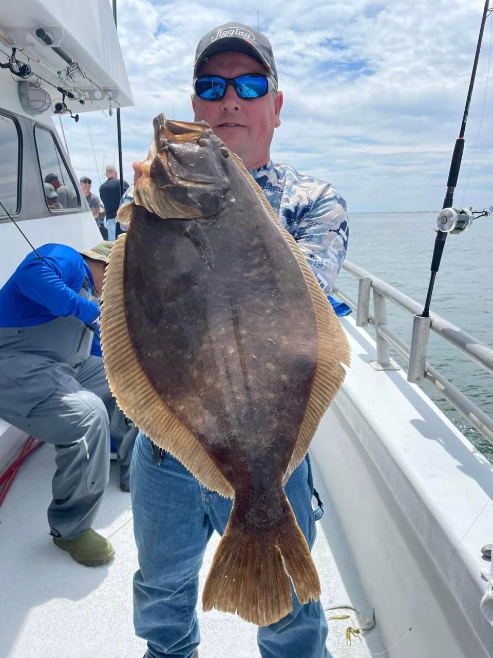 A fisherman holds his catch of a fluke on board the Gambler part boat.