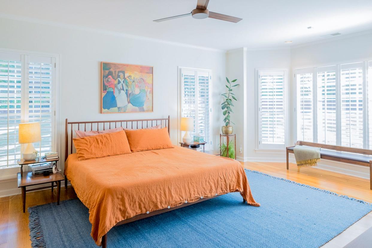 The primary bedroom is a beautiful space that features plantation shutters and a vibrant color palette.
