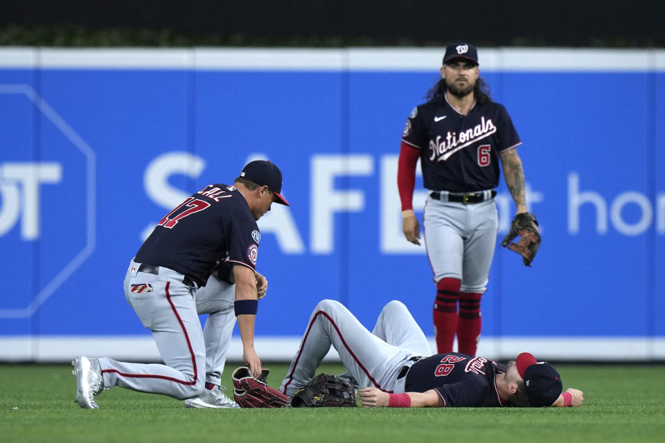 Washington Nationals center fielder Alex Call (17) and second baseman Michael Chavis (6) check on right fielder Lane Thomas after Call and Thomas collided attempting to catch a ball hit by Miami Marlins' Jorge Soler during the first inning of a baseball game, Friday, Aug. 25, 2023, in Miami. (AP Photo/Wilfredo Lee)