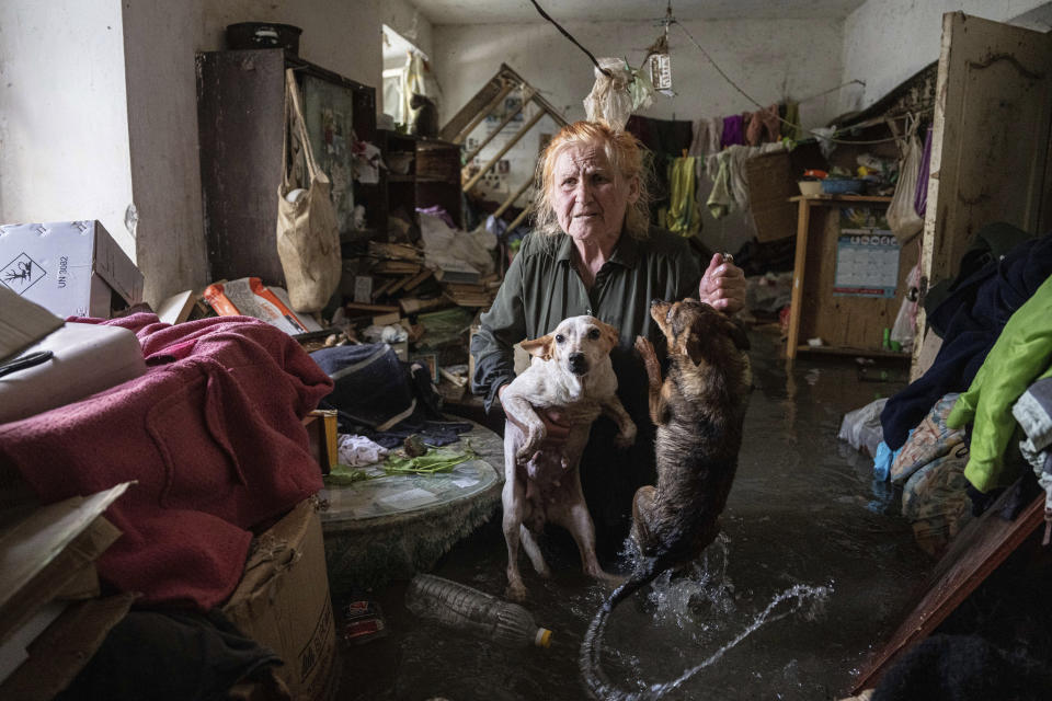 Local resident Tetiana holds her pets, Tsatsa and Chunya, as she stands inside her house that was flooded after the Kakhovka dam blew up overnight, in Kherson, Ukraine, Tuesday, June 6, 2023. Ukraine on Tuesday accused Russian forces of blowing up a major dam and hydroelectric power station in a part of southern Ukraine that Russia controls, risking environmental disaster. (AP Photo/Evgeniy Maloletka)