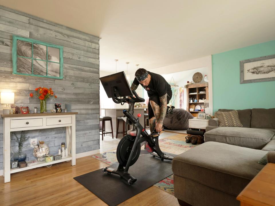 A man riding a Peloton bike in his living room.