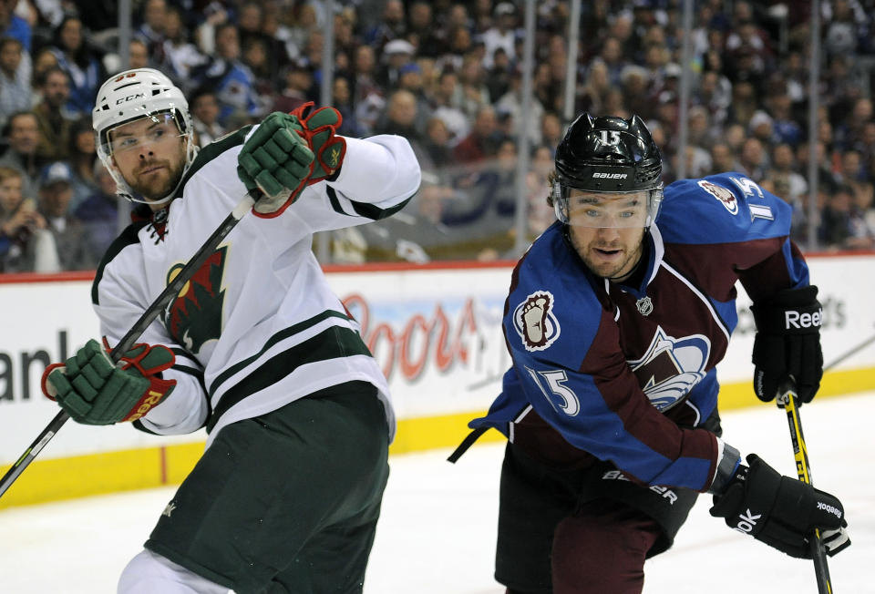 Minnesota Wild defenseman Nate Prosser, left, and Colorado Avalanche right wing P.A. Parenteau, right, fight for the puck in the first period in Game 5 of an NHL hockey first-round playoff series on Saturday, April 26, 2014, in Denver. (AP Photo/Chris Schneider)