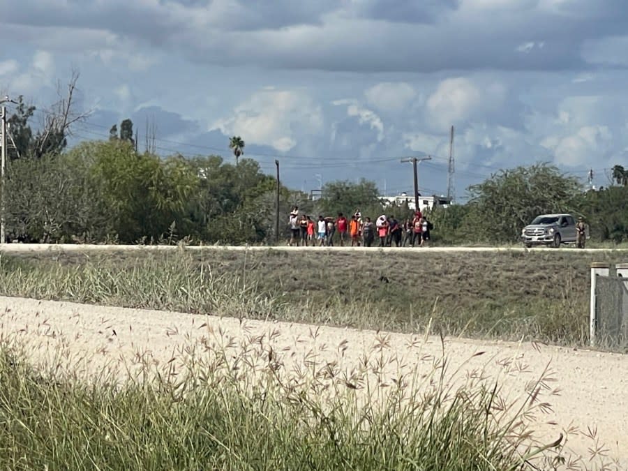 Law enforcement officials walk a group of migrants on Oct. 1, 2023, to Camp Monument in Brownsville, Texas, for processing after they crossed illegally into the United States from Matamoros, Mexico. (Sandra Sanchez/Border Report)