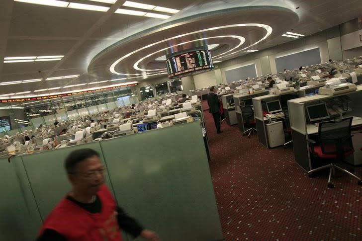 A floor trader (L) walks in the trading hall of the Hong Kong Stock Exchange November 23, 2010. REUTERS/Tyrone Siu/Files