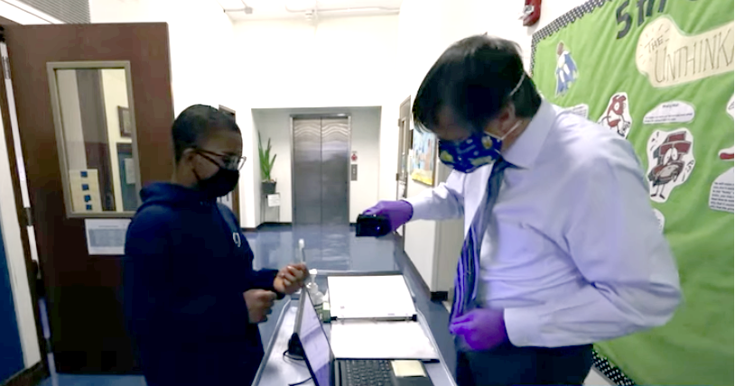 A student waits as a worker scans a COVID-19 saliva test vial at Chicago Jesuit Academy. (SHIELD Illinois)