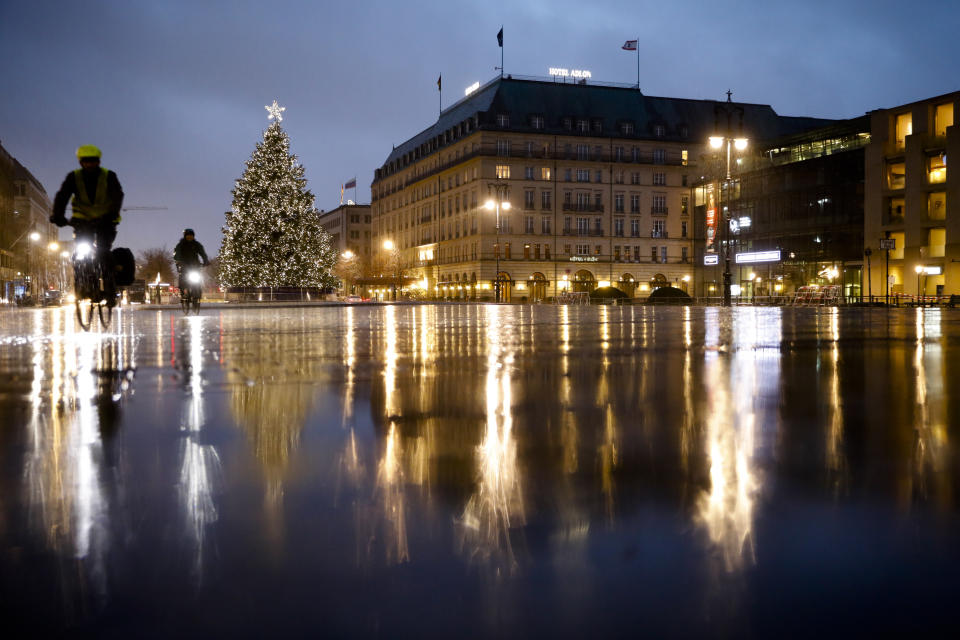 Rain covers the deserted Pariser Platz at the Brandenburg Gate in Berlin, Germany, Tuesday, Dec. 22, 2020. The Robert Koch Institute, Germany's national disease control agency, figures for Germany: 19,528 new cases, a week ago it was14,432 and another 731 deaths. (AP Photo/Markus Schreiber)