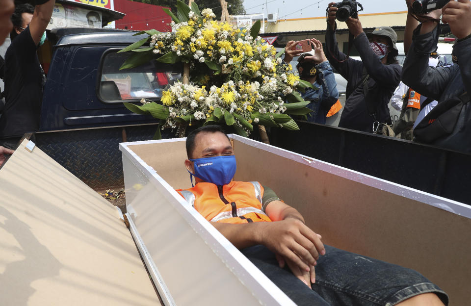 A man lays inside a mock coffin as punishment for violating city regulations requiring people to wear face masks in public places as a precaution against the new coronavirus outbreak in Jakarta, Indonesia, Thursday, Sept. 3, 2020. (AP Photo/Achmad Ibrahim)