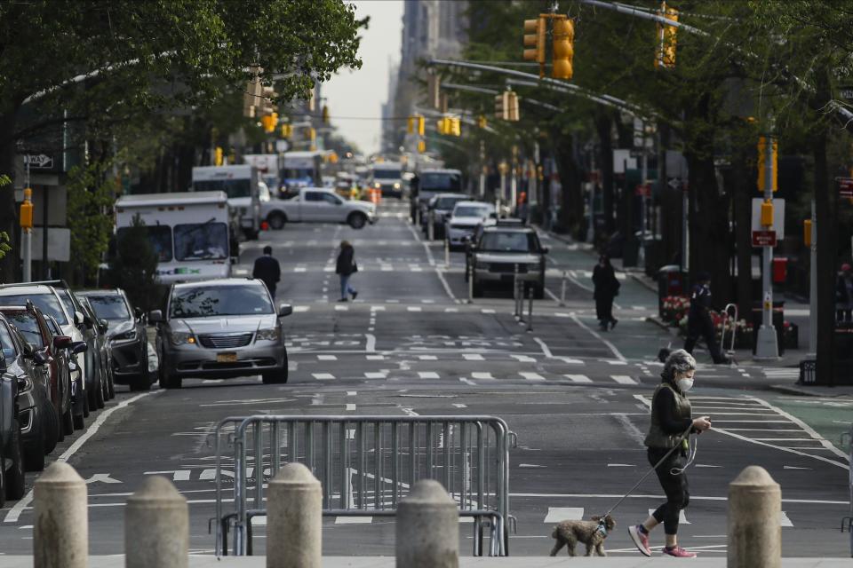 A woman wears a protective mask while walking her dog along Washington Square North, Tuesday, April 21, 2020, in New York. (AP Photo/Frank Franklin II)