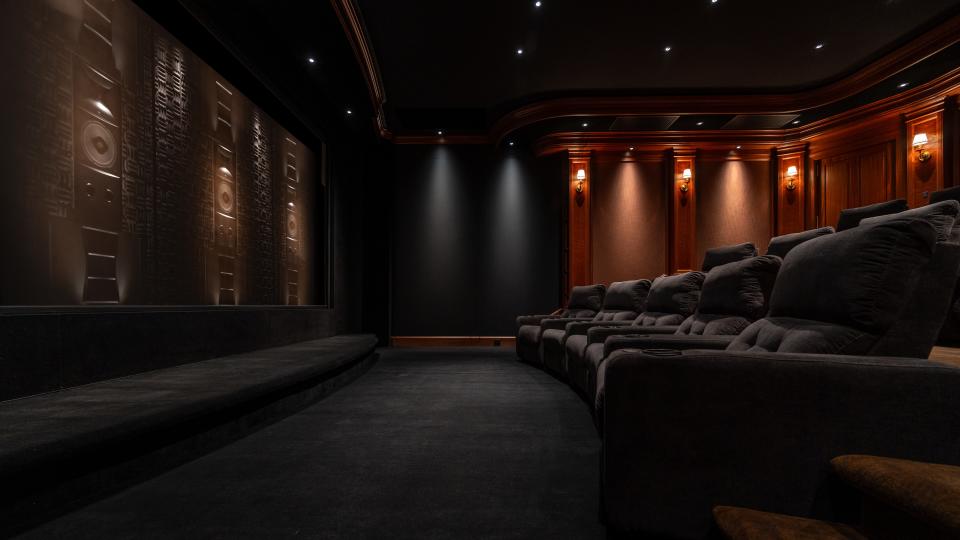 Home theater Hahn theater with seating, light sconces, screen revealing in-wall speakers behind