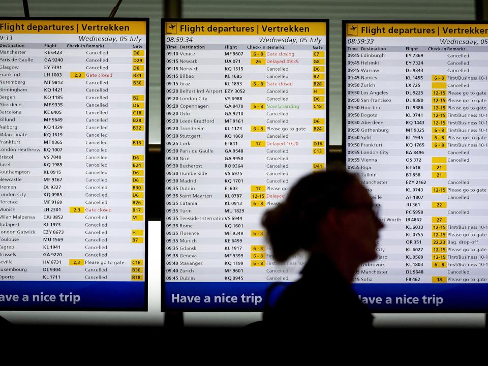 A woman stands in front of flight information boards that display canceled flights at Schiphol Airport in The Netherlands.