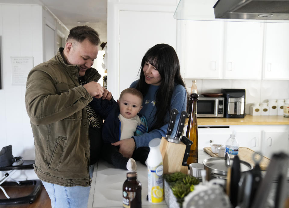 Resident and board member of the mobile home park Bob’s and Jamestown Homeowners Cooperative, Gadiel Galvez, 22, helps his wife Leslie, 24, dress their 9-month-old son, Ezra, on Saturday, March 25, 2023, in Lakewood, Wash. When residents learned the park’s owner was looking to sell, they formed a cooperative and bought it themselves amid worries it would be redeveloped. Since becoming owners in September 2022, residents have worked together to manage and maintain the park. (AP Photo/Lindsey Wasson)