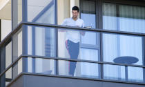 Serbia's Novak Djokovic stands on the balcony at his accommodation in Adelaide, Australia, Tuesday, Jan. 19, 2021. Australian Open tournament director Craig Tiley defended Djokovic for appealing to Australian Open organizers to ease restrictions so players could move to private residences with tennis courts. (Morgan Sette/AAP Image via AP)