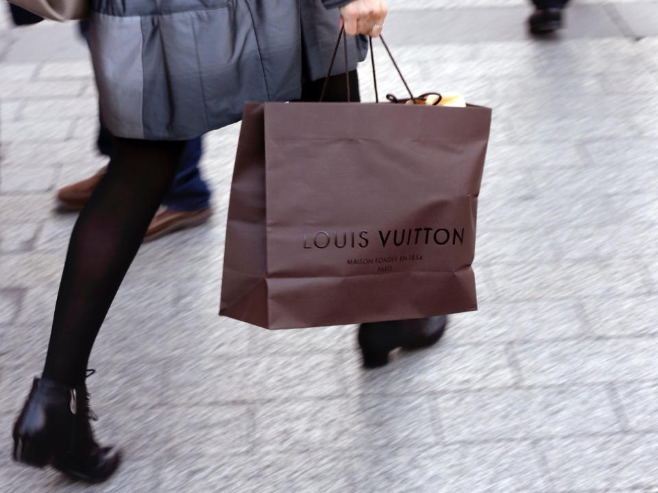 A woman walks with a Louis Vuitton shopping bag as she leaves a Louis Vuitton store in Paris September 24, 2013.