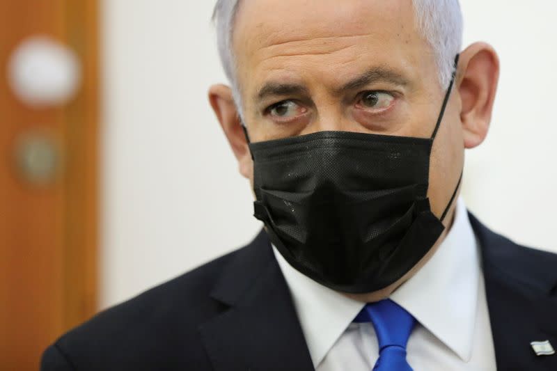 FILE PHOTO: Israeli Prime Minister Benjamin Netanyahu, wearing a face mask, looks on as his corruption trial resumes, at Jerusalem's District Court