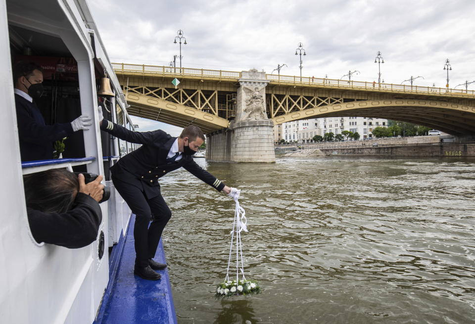 A wreath is laid on River Danube by a sailor during an ecumenical commemoration marking the second anniversary of a fatal boat accident on River Danube next to Margaret Bridge, in Budapest, Hungary, Saturday, May 29, 2021. Over two dozen South Korean tourists died after their tour boat collided with a river cruise ship on the Danube River. (Balazs Mohai/MTI via AP)