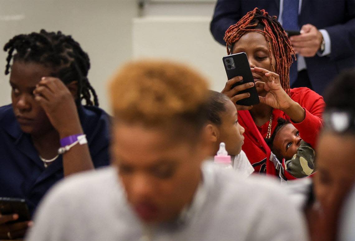 Jenice Davis, 39, tries to use her phone to engage in the breakout session while her 4-month old daughter, Ja’Majesty Allen, is suspended in baby carrier as Broward County Public Schools held the first of three town halls to discuss with the community the possibility of closing schools in 2025 due to under-enrollment at Fort Lauderdale High School on Thursday, February 8th, 2024.