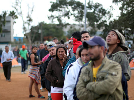 FILE PHOTO: Migrants, part of a caravan of thousands from Central America trying to reach the United States, queue for aid in a shelter in Tijuana, Mexico, November 19, 2018. REUTERS/Hannah McKay/File Photo